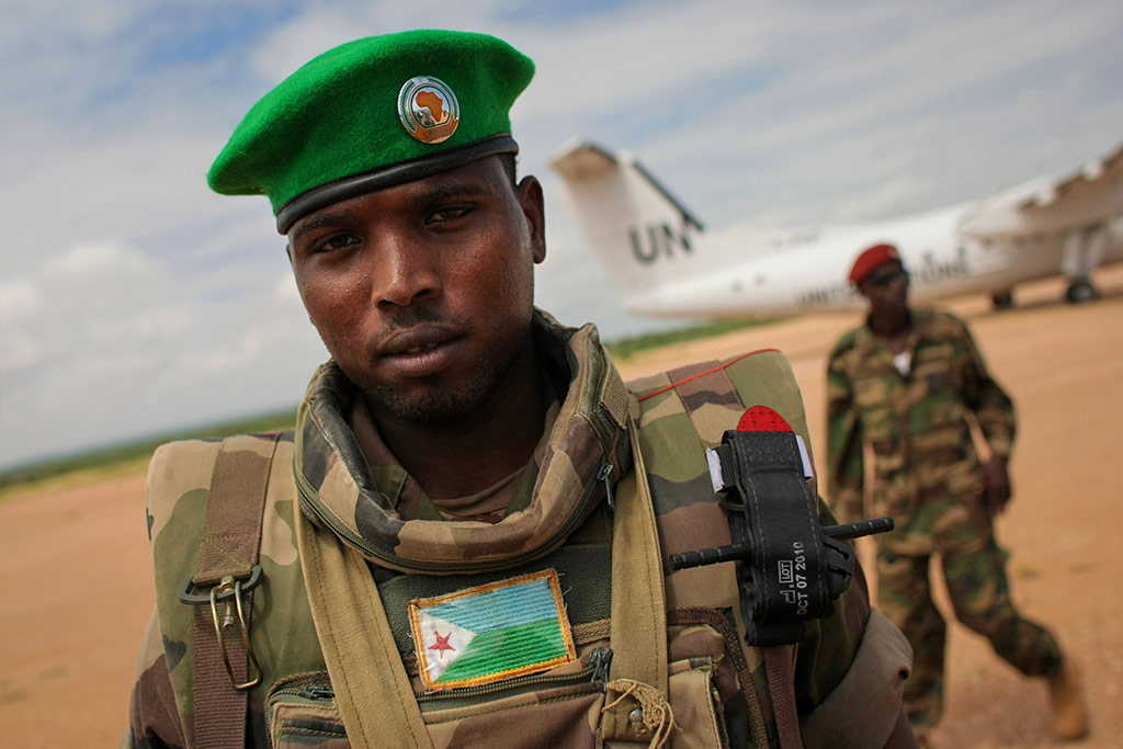 A soldier of the Djiboutian Contingent serving with the African Union Mission in Somalia (AMISOM) stands guard as a 51Թ aircraft prepares for take-off from Belet Weyne Airport. AU PHOTO/Stuart Price
