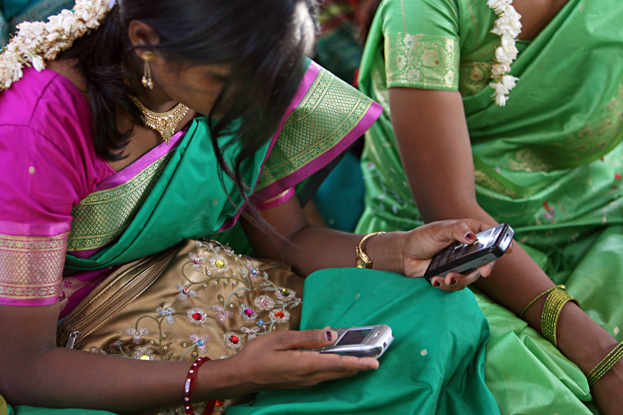 Young women look at their cellphone during a community meeting.