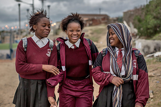 Tres ni?as estudiantes de primaria caminando por la carretera en Ciudad del Cabo, Sudfrica.