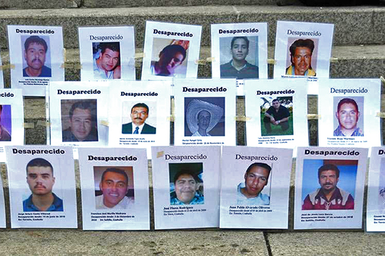 Photos of disappeared persons lined up on concrete stairs.