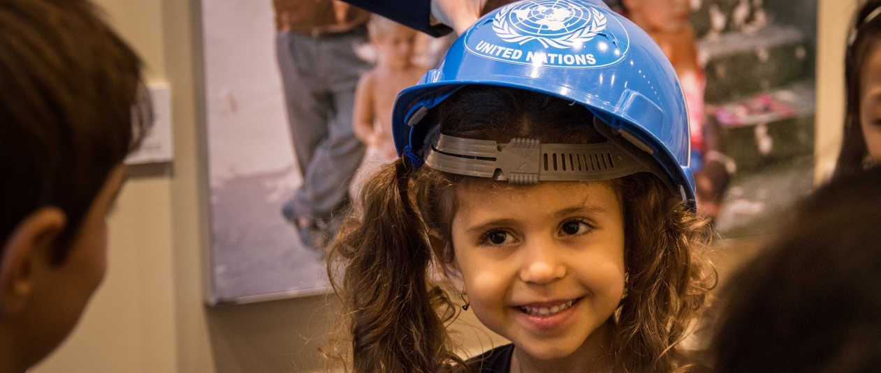 Une jeune fille participant au UN Kids Tour porte un casque bleu de l'ONU.