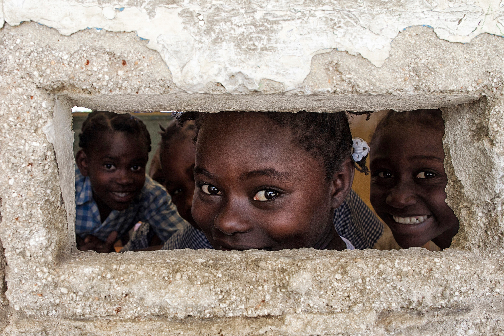 A group of Haitian children looking out of a small window.