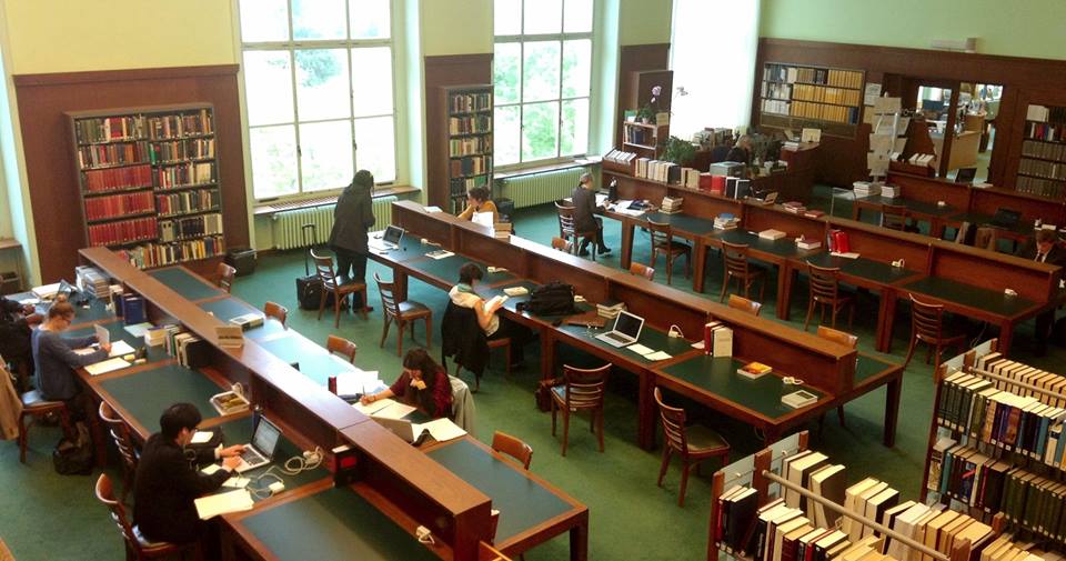 Vista desde arriba de la biblioteca con escritorios de estudio y estantes para libros.