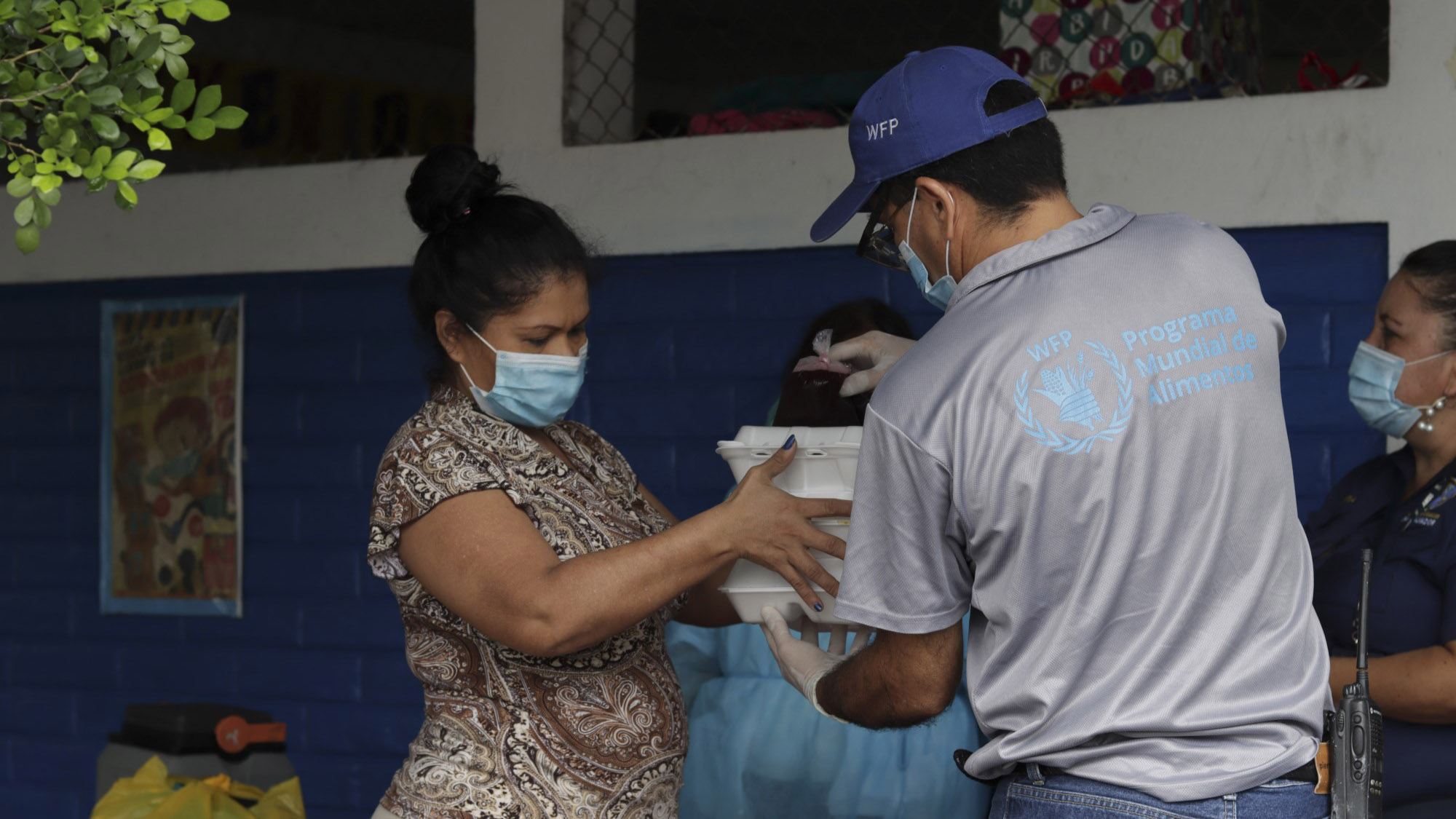 Un employ du Programme alimentaire mondial distribue de la nourriture  une femme au Salvador