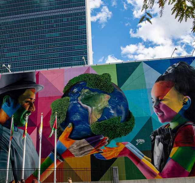 Photo de la fresque d'Eduardo Kobra au Sige de l'ONU reprsentant un homme offrant un globe  une jeune fille
