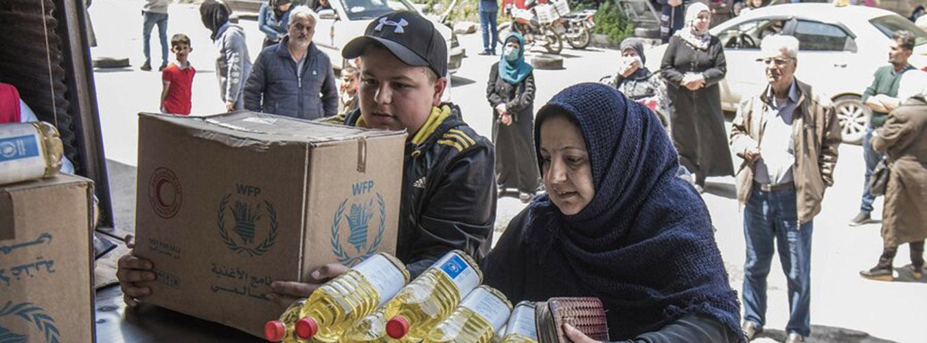 Une famille collecte des rations alimentaires  un point de distribution du PAM en Syrie.