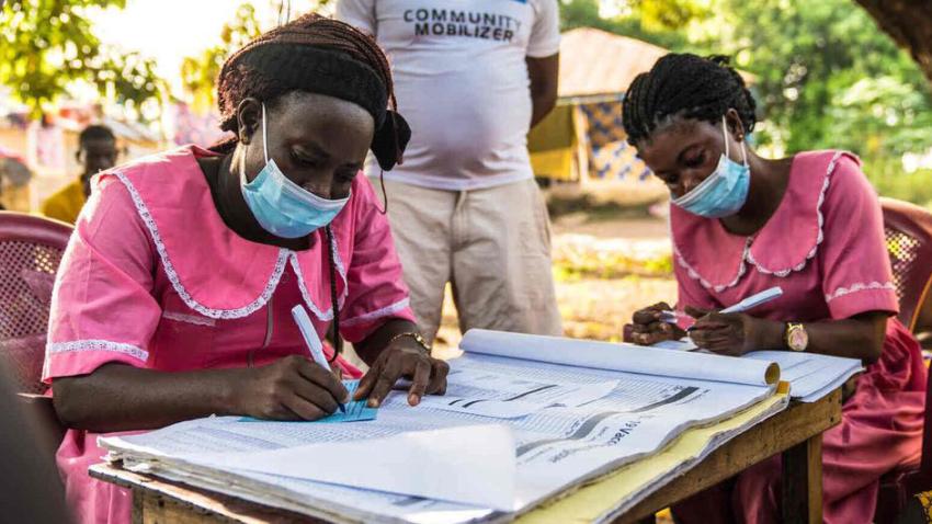 health workers filling out records at a table outdoors