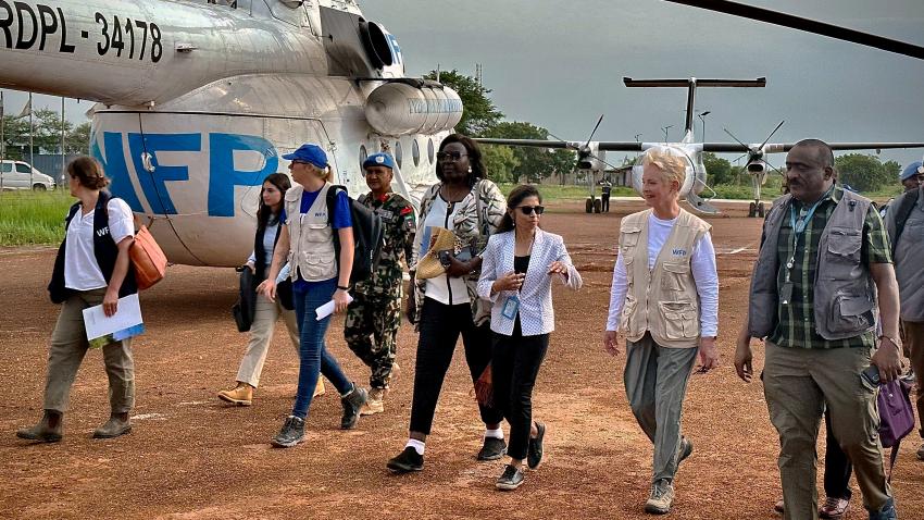 Cindy walks with several others infront of a helicopter marked with the acronym WFP